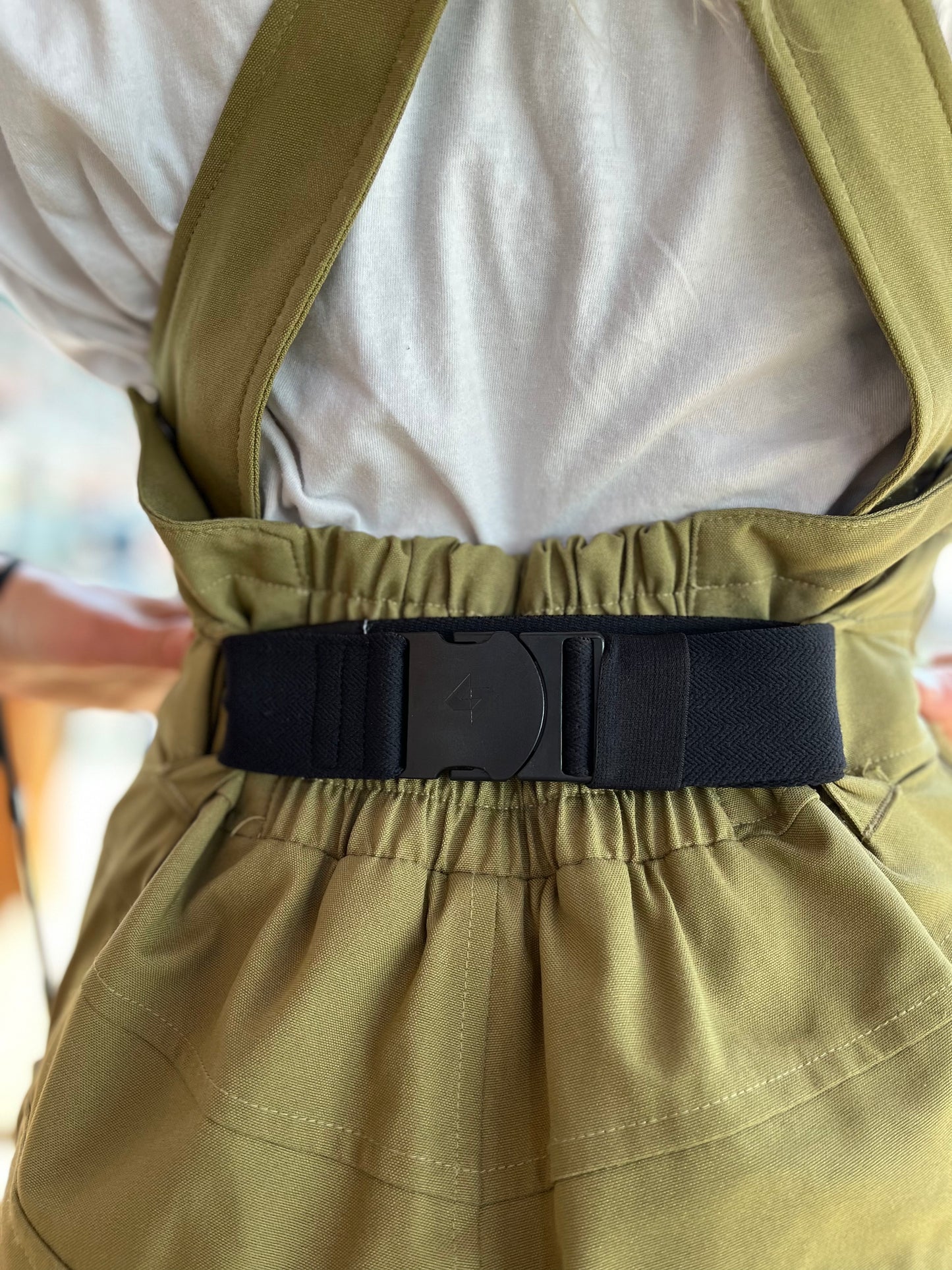 girl in a green ski outfit wearing a black bib belt
