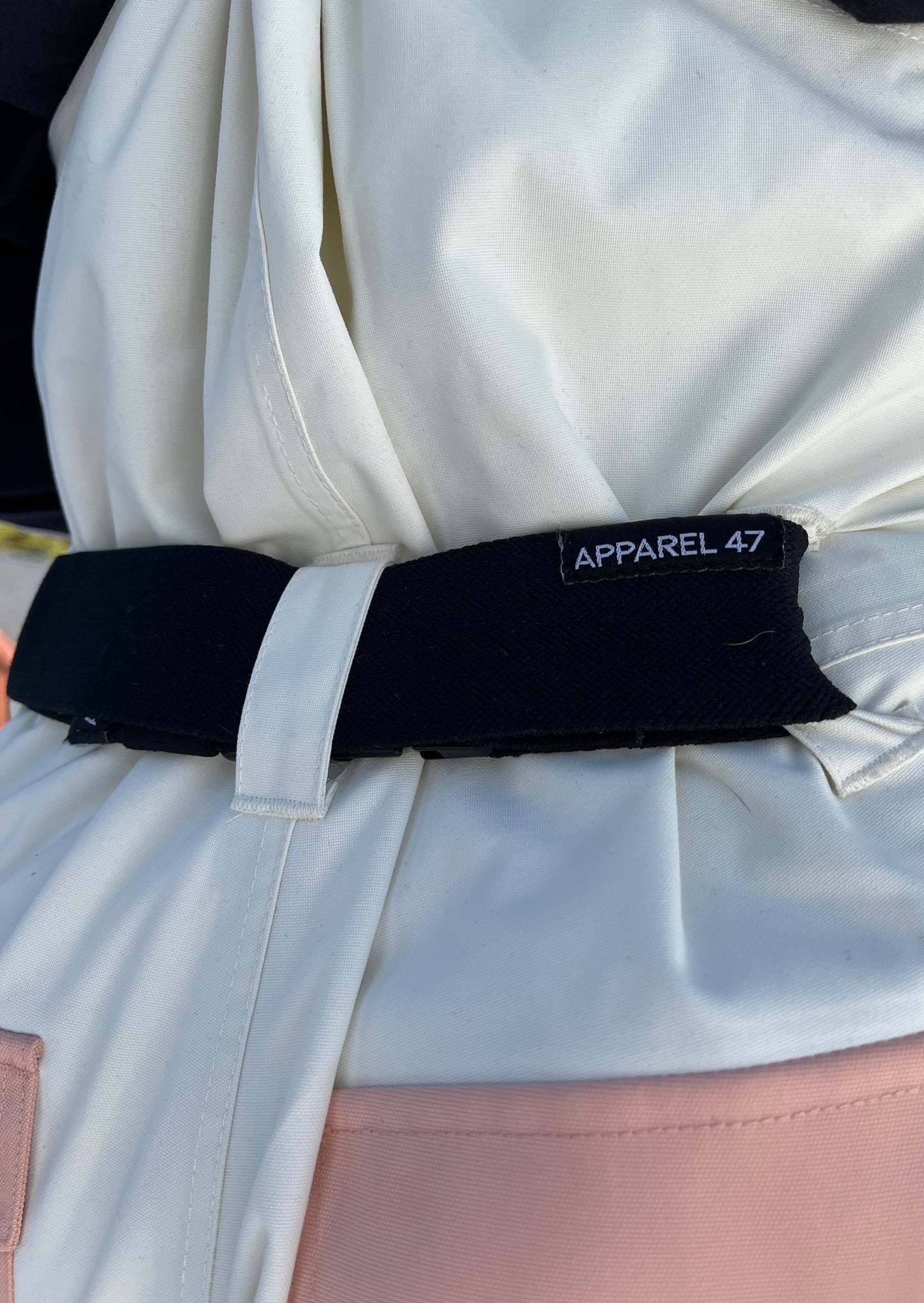 a girl facing backward in a pink and white ski bib wearing a black bib belt