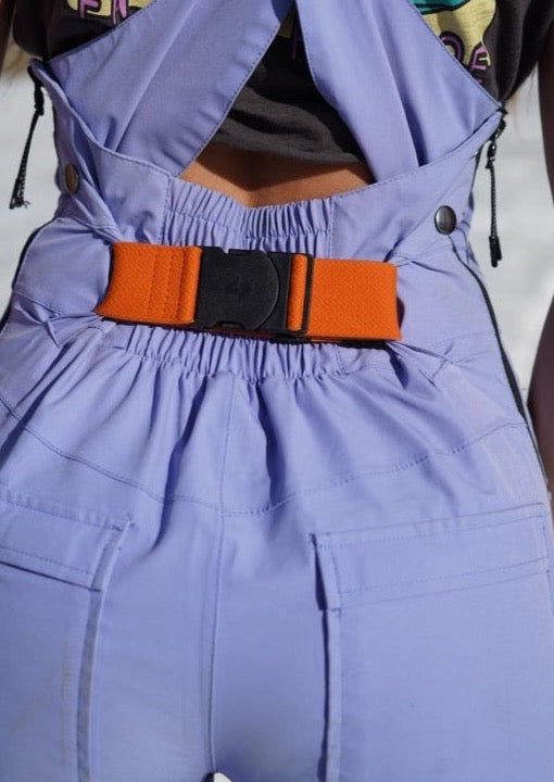 a girl facing backwards wearing a purple ski bib with an orange bib belt