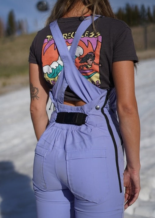 a girl facing backward wearing a purple ski bib and a black bib belt